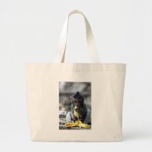 Cute baby macaque monkey eating banana tote bags