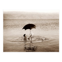 Man reading under umbrella in the Dead Sea Postcard