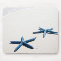Two blue starfish at water's edge on tropical mousepads