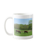 Two horses in field with trees and pond mug