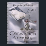 25th Ordination Anniversary Cross Host Notebook<br><div class="desc">Celebrate a 25th Ordination Anniversary with this beautiful silver satin background and cross with red details. A paten of hosts is seen behind the name and 25th Year. Customise with the name for a truly personal Ordination Anniversary Gift! Party supplies and customisable items are available for a memorable celebration!</div>