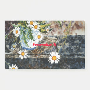 A blue and white pot of wild daisies on a shelf post-it notes