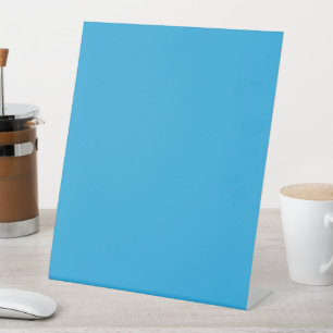 a blue background with a black and white cat on to pedestal sign