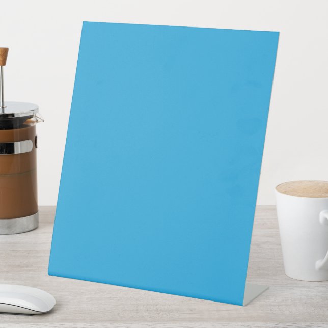 a blue background with a black and white cat on to pedestal sign (In SItu)