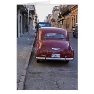 A classic old red Peugeot car parked on a street
