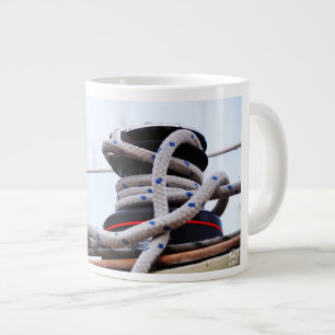 A close-up of a sailboat winch on a boat. large coffee mug