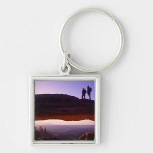 A couple watches sunrise from atop Mesa Arch in Key Ring