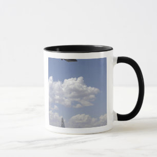 A CV-22 Osprey flies over a C-130 Hercules Mug
