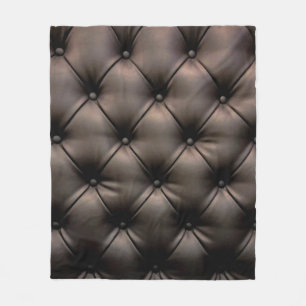 A dark leather cushion background, from a car seat fleece blanket