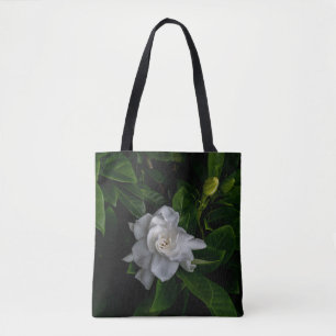 A delicate white flower blooms tote bag