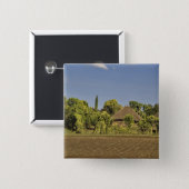 A farmed field in front of thatched roof houses 15 cm square badge (Front & Back)