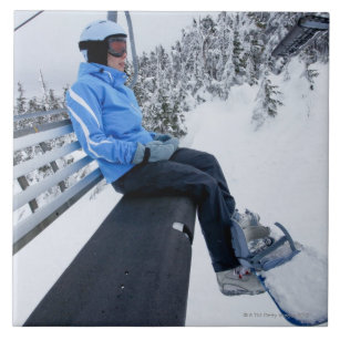 A female snowboarder rides the chair lift in New Tile