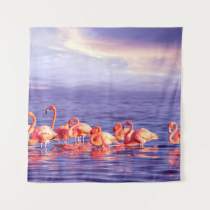 A flock of beautiful pink flamingos against a purp tapestry