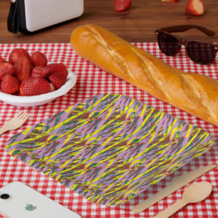 A fluffy grey cat with green eyes sits on a window paper plate