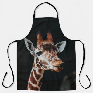 A GIRAFFE AT CALGARY ZOO POKING HIS TONGUE OUT APRON