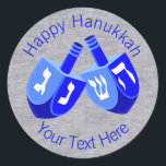 A Hanukkah Dreidels In Blue Cheerful Kids Design Classic Round Sticker<br><div class="desc">Use these fun round Hanukkah stickers as party favours, to dress up a gift package, to seal envelopes or anything else your DIY self can imagine. The double Dreidel design in white and bright blues is my original artwork so these Chanukah stickers are one-of-a-kind. Set on a faux bling silver...</div>