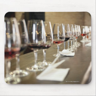 A long row of wine glasses set up so a large mouse pad