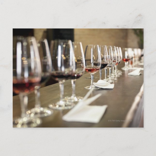 A long row of wine glasses set up so a large postcard (Front)
