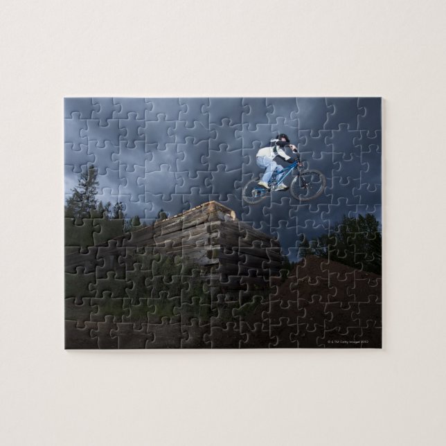 A mountain biker jumps off a log cabin in Idaho. Jigsaw Puzzle (Horizontal)