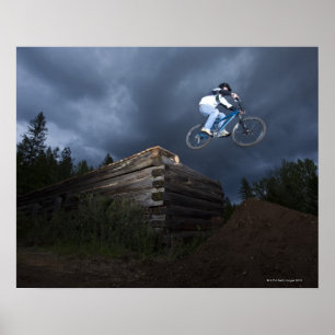 A mountain biker jumps off a log cabin in Idaho. Poster