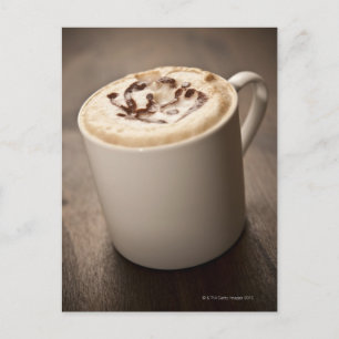 A mug of Cappuccino coffee topped with melted Postcard