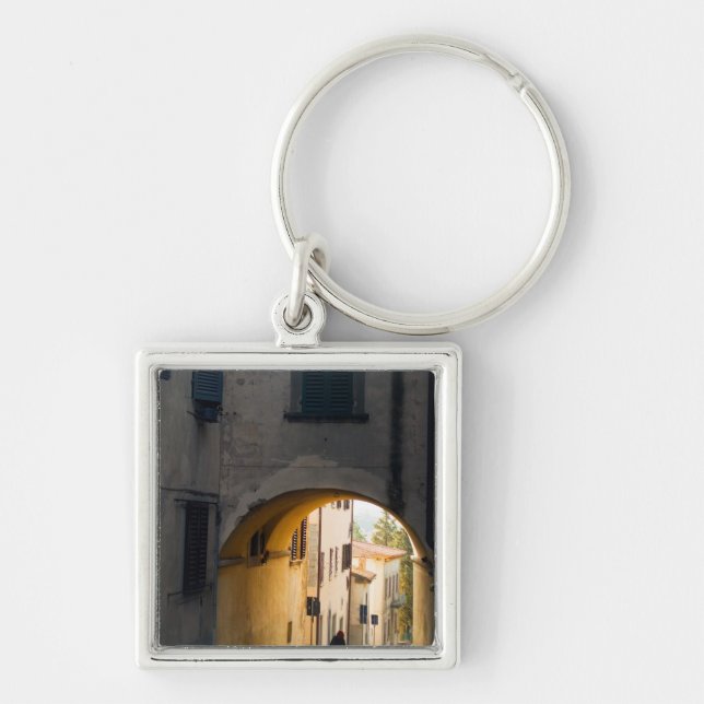 A person walking under an arch, down a hill in key ring (Front)