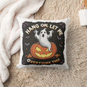 A playful ghost pondering above a jack-o'-lantern cushion