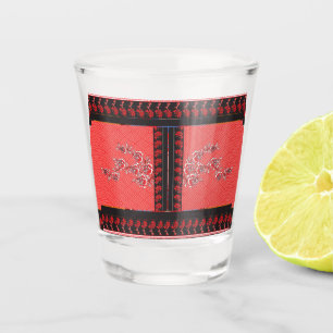 a red and black pattern with flowers on it shot glass