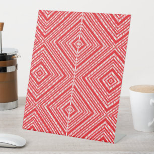 a red and white background with a diamond pattern pedestal sign