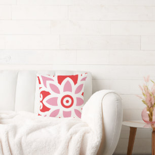 a red and white pattern with a flower on it cushion