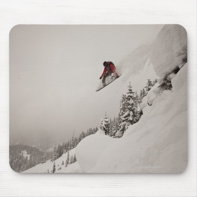 A snowboarder jumps off a cliff into powder in mouse pad (Front)