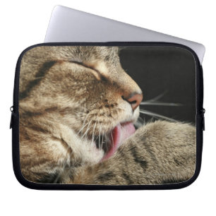 A tabby cat licking his paw. laptop sleeve