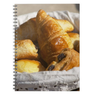 A wicker breakfast basket with croissants, and notebook