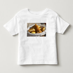 A wicker breakfast basket with croissants, and toddler T-Shirt