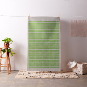A woman wearing a grey sweater and glasses sits by fabric