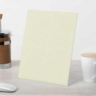 a yellow and white background with small circles pedestal sign