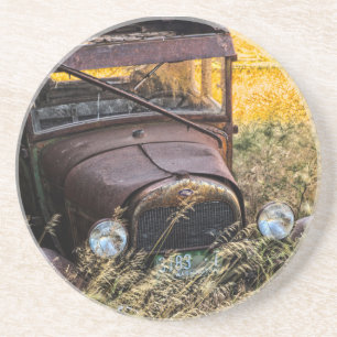 Abandoned old car in tall grass coaster