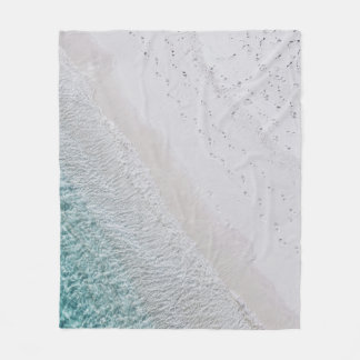 AERIAL PHOTOGRAPHY OF WHITE SAND SEASHORE AND GREE FLEECE BLANKET