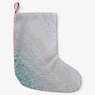 AERIAL PHOTOGRAPHY OF WHITE SAND SEASHORE AND GREE SMALL CHRISTMAS STOCKING