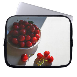 Aesthetic still life with ripe cherries on a white laptop sleeve