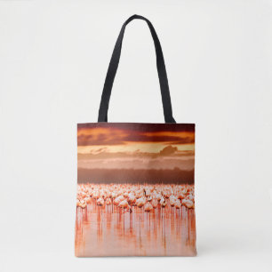African flamingos in the lake over beautiful sunse tote bag