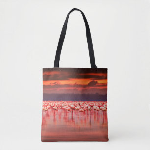 African flamingos in the lake over beautiful sunse tote bag