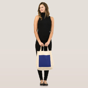 an aeroplane flying in the sky with a blue backgro tote bag