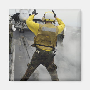 An aircraft director signals a F/A-18C Hornet Magnet