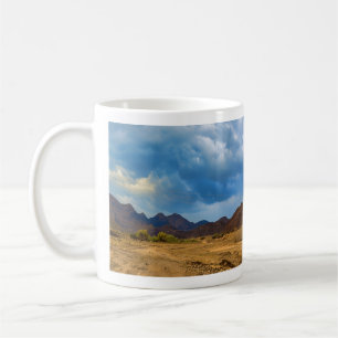 An arid landscape under a dramatic, cloudy sky coffee mug
