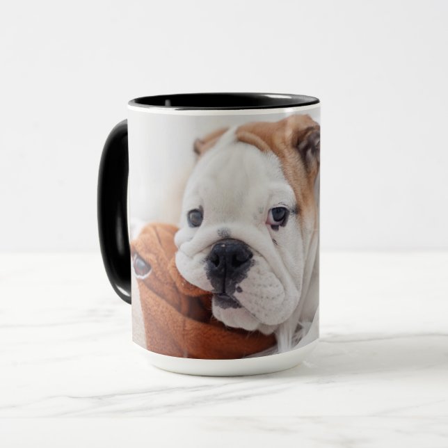 An English Bulldog Puppy Playing With A Bulldog Mug (Front Left)
