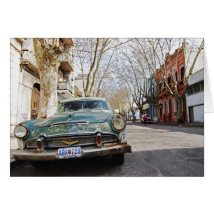 An old car rusty and flaky colour parked in the
