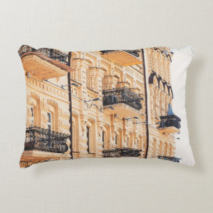 An old yellow house with wrought-iron balconies. f decorative cushion