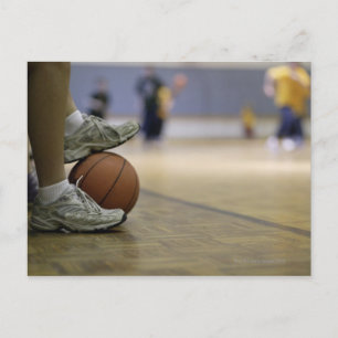 Basketball player holding ball with feet postcard