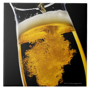 Beer been poured into glass, studio shot ceramic tile
